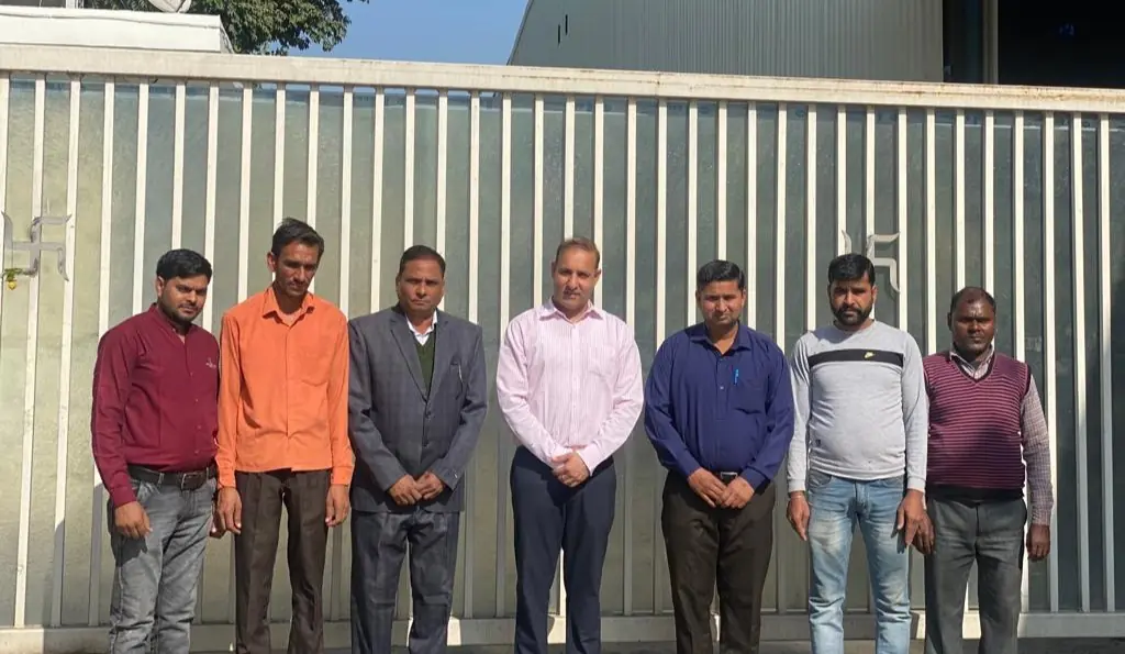 The Kumar Veneers team, seven people standing together in front of the works gate in Jagadhri